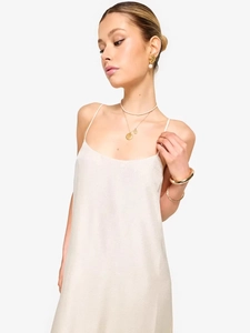 Elegant backless off-white slip dress with gold jewelry accessories for a chic summer look