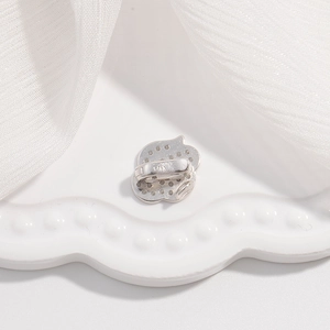 Macro detail of S925 silver flower clasp with white zircon stones on silk fabric
