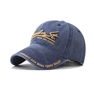 Detail showing the intricate gold embroidery and distressed texture on a blue cotton cap