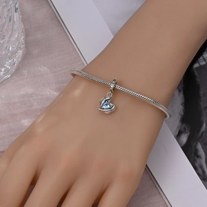 Close-up of silver snake chain bracelet with heart charm and blue opal stone on wrist