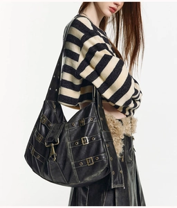 Detail of vintage black hobo bag showing aged leather texture and bronze metal buckles