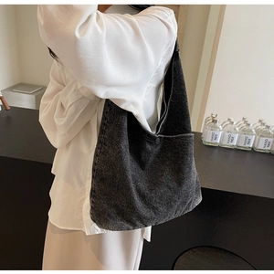 Detail of a black washed denim tote bag showing the button closure and fabric texture