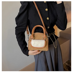 Close-up of brown suede and white faux shearling patchwork shoulder bag with leather handle