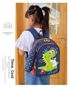 Detail of navy blue kids backpack with dinosaur print worn by a young girl outdoors