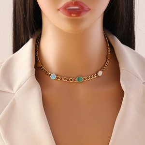 Close-up of gold chain necklace with colorful turquoise, malachite and shell pendants
