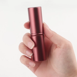 Macro detail of wine red retractable makeup brush with a sleek matte metal casing