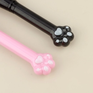Détail des manches de pinceaux de maquillage patte de chat en noir et rose avec coussinets