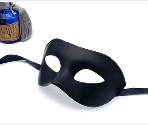 Detail view of a matte black half-face masquerade mask with adjustable ribbon straps