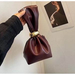 Close-up of deep burgundy drawstring pouch with a prominent gold metal ring detail