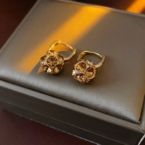 Close-up of gold-plated ball earrings with amber crystal inlays on a jewelry box