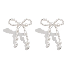 Macro view of bow-shaped pearl earrings featuring long tassels and retro elegant design