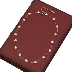 Detalle de collar de perlas de imitación con corazones y cadena dorada de acero inox