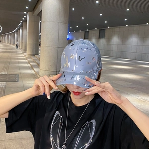 Close-up of shiny silver baseball cap with purple graffiti print worn by model