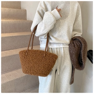 Sac à main en peluche caramel avec fines anses en cuir marron porté par un modèle