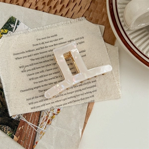 Macro shot of white pearlescent square acetate hair claw clip on vintage background