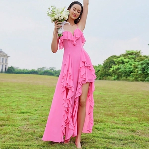 Detail of rose pink V-neck dress with layered ruffles and high slit on grassy background