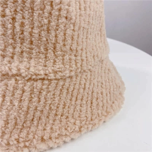 Close-up of thick beige lamb wool fabric texture on a winter fisherman hat