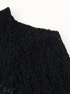 Detailed macro view of black bodysuit featuring embossed 3D bubble texture fabric detail
