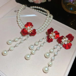 Detail of red flower pendant with pearl beads and matching earrings in a jewelry box