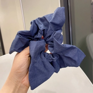 Detail of blue denim fabric scrunchie with soft pleats for ponytail styling