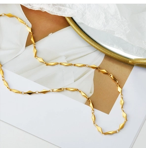 Macro view of geometric gold fishbone necklace with diamond-shaped metal links