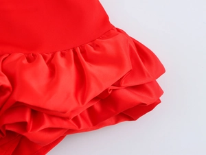 Détail du tissu en satin rouge avec volants superposés sur une robe courte à col carré