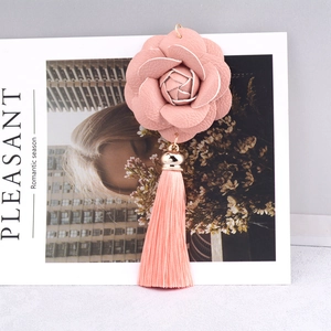Close-up of pink PU leather camellia flower keychain with silk tassel and gold buckle
