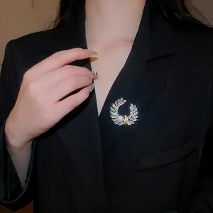 Elegant laurel leaf brooch with 18k gold plating, white zircons and pearl on black suit