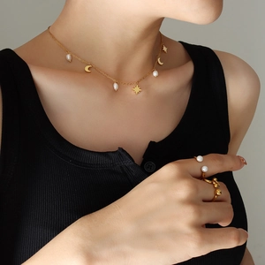 Elegante collar de oro con dijes de estrella y luna y perlas de agua dulce en una modelo
