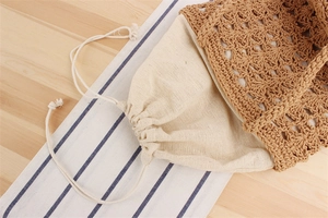 Detail of hollow crochet woven handbag featuring a cream cotton drawstring inner lining