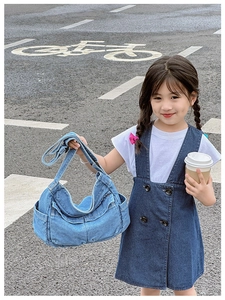 Girl wearing a blue vintage wash denim crossbody bag with adjustable strap in street setting