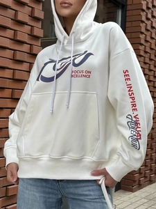Streetwear white hoodie with Focus On Excellence prints against a red brick wall background
