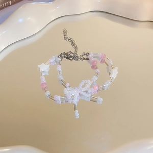Detailed macro view of pink beaded bow bracelet with star charms on a mirror tray
