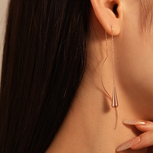 Close-up of rose gold long drop earrings with elegant chain and water droplet pendant