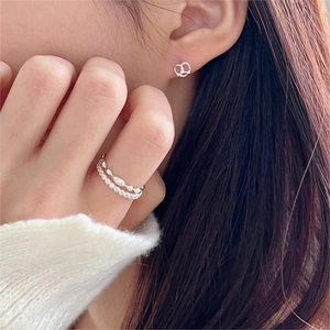Close-up of a 925 sterling silver layered zircon ring and knot earrings on a model