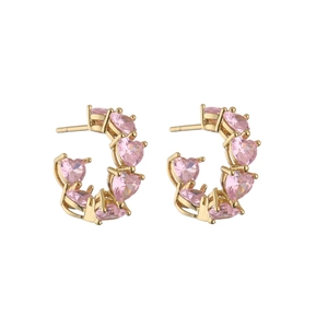 Detailed macro view of pink heart-shaped cubic zirconia stones on gold C-shaped earrings