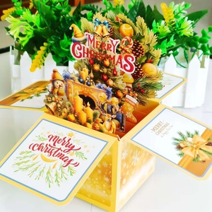 Macro detail of 3D pop-up Christmas card featuring a golden Christmas tree and fireplace