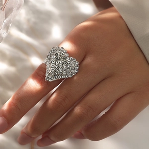 Macro detail of a sparkling heart-shaped ring with pavé crystals on a model's hand