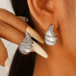 Detail shot of a silver conch shell stud earring worn on a model's ear for sea style