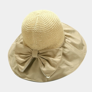 Detail of summer straw hat with large bow and zipper for foldable storage feature