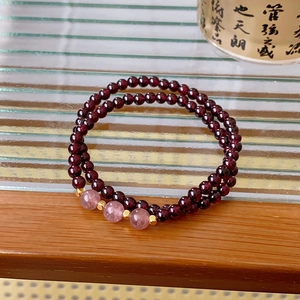 Macro shot of double-layer garnet and strawberry quartz beaded bracelet on wood