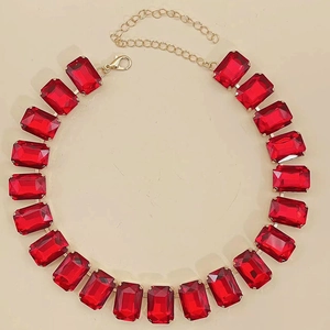 Detail view of large red rectangular crystal gemstones set in a polished gold chain link