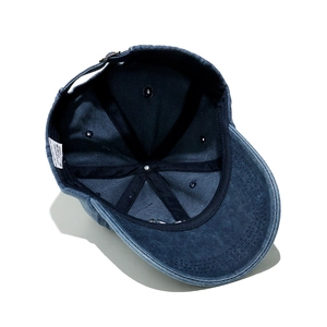 Detail of 100% cotton washed denim cap interior showing six-panel stitch and care label