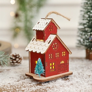 Luminous red wooden Christmas house ornament with LED light on snow-covered ground