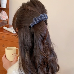 Détail d'une pince à cheveux banane à carreaux bleu foncé stylisée sur un chignon