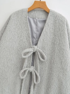 Detailaufnahme der grauen Wolljacke mit Schleifenverschluss und Seidenfutter-Textur