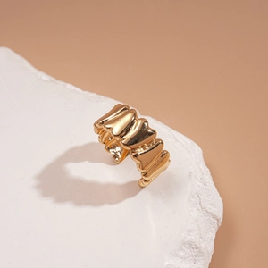 Détail d'une bague dorée texturée sur pierre décorative blanche avec fond chaleureux