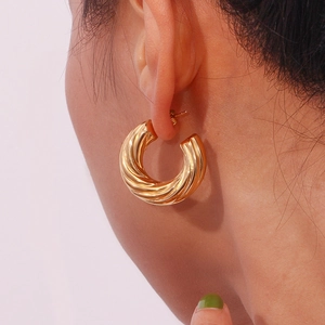 Close-up of woman wearing elegant 18K gold plated hollow C-shape twisted rope earrings