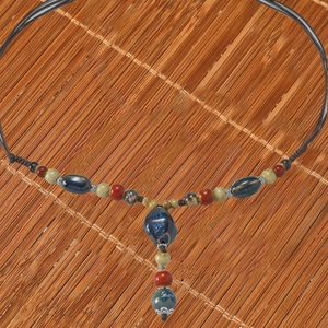 Handmade woven ceramic beaded long necklace with colorful stones on bamboo mat