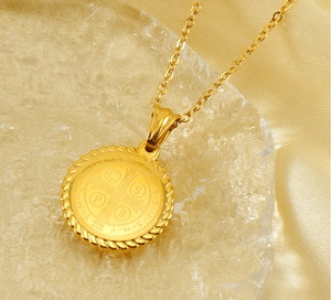 Macro view of gold St. Benedict medal pendant with twisted rope border on satin